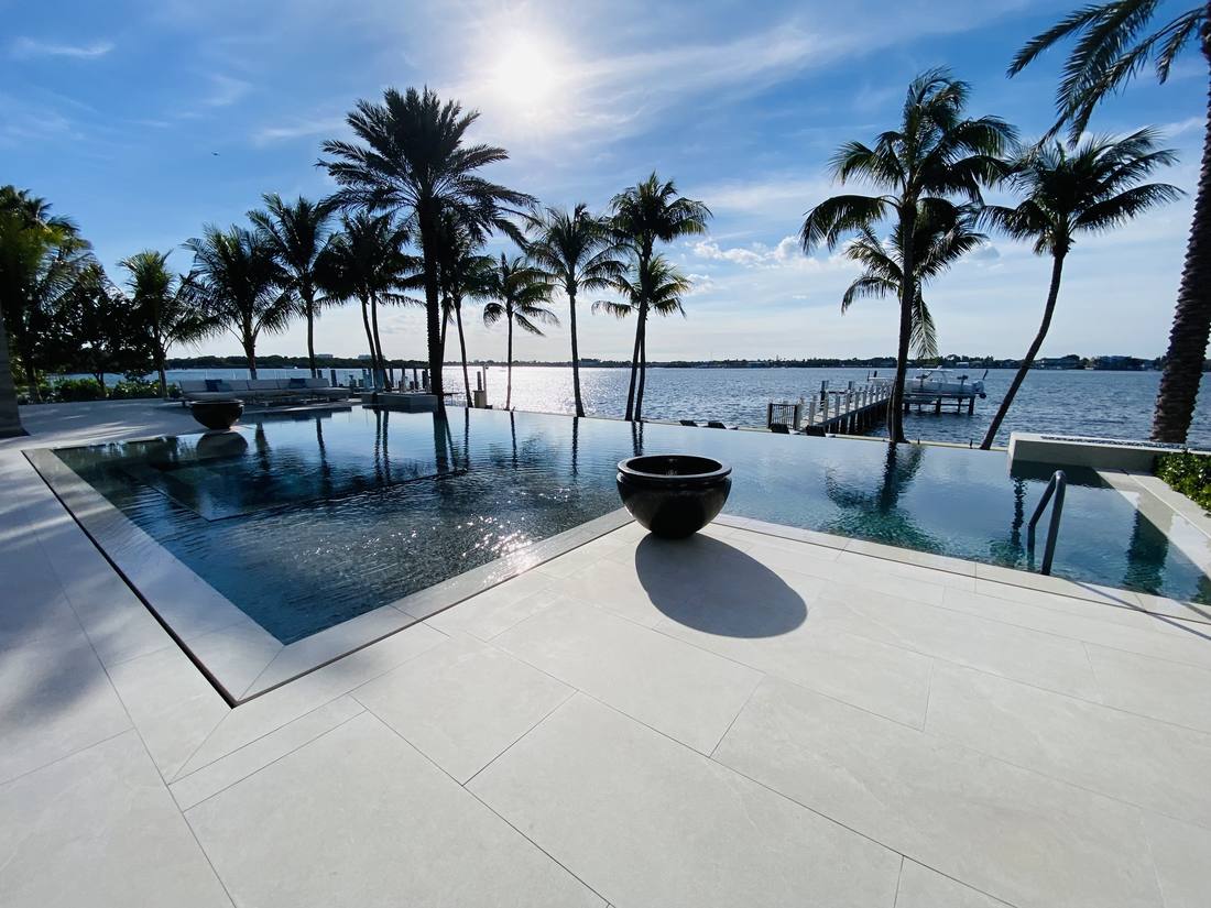 Finished gunite pool with an infinity edge and travertine deck at dusk