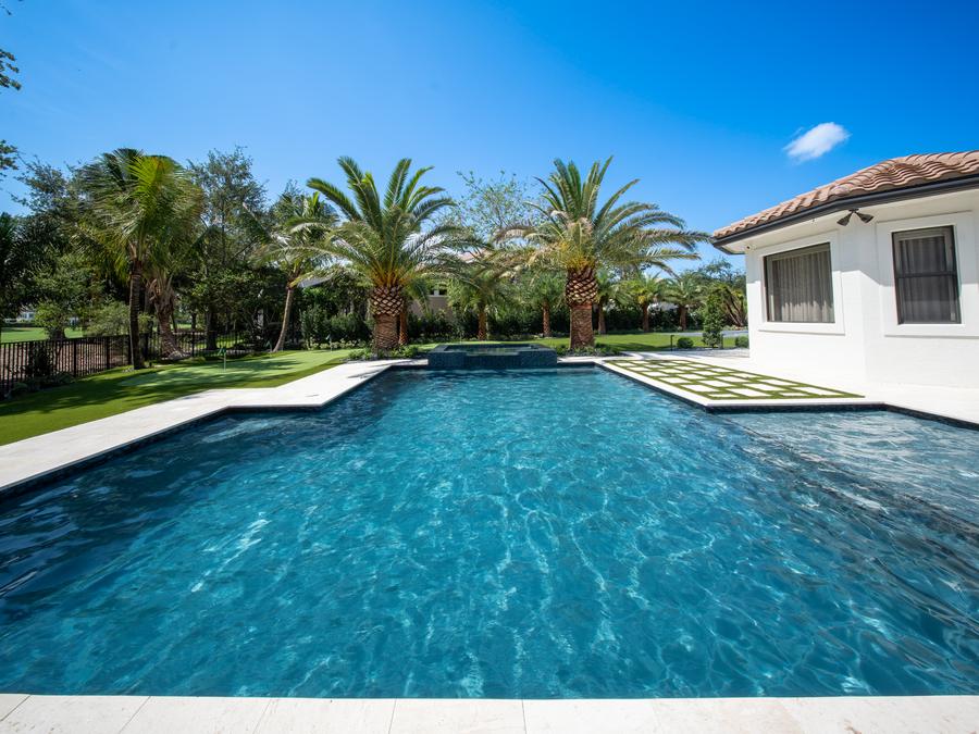 Large geometric gunite pool with travertine deck and palms