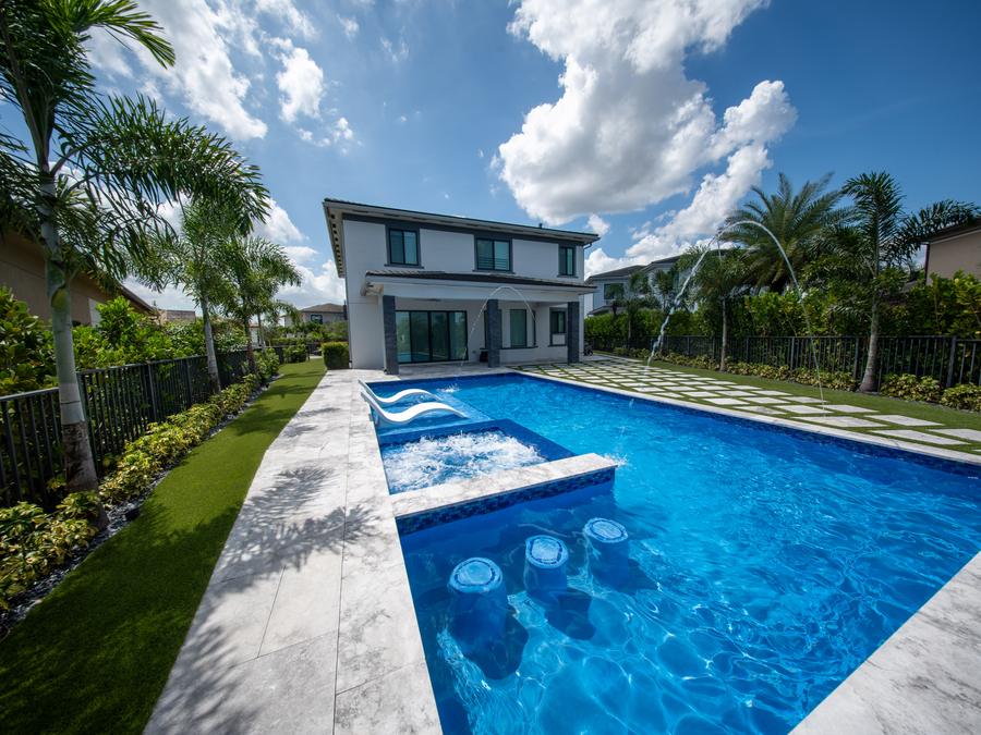 Rectangular lap pool with a raised spa and sheer descents beside a modern two-storey home