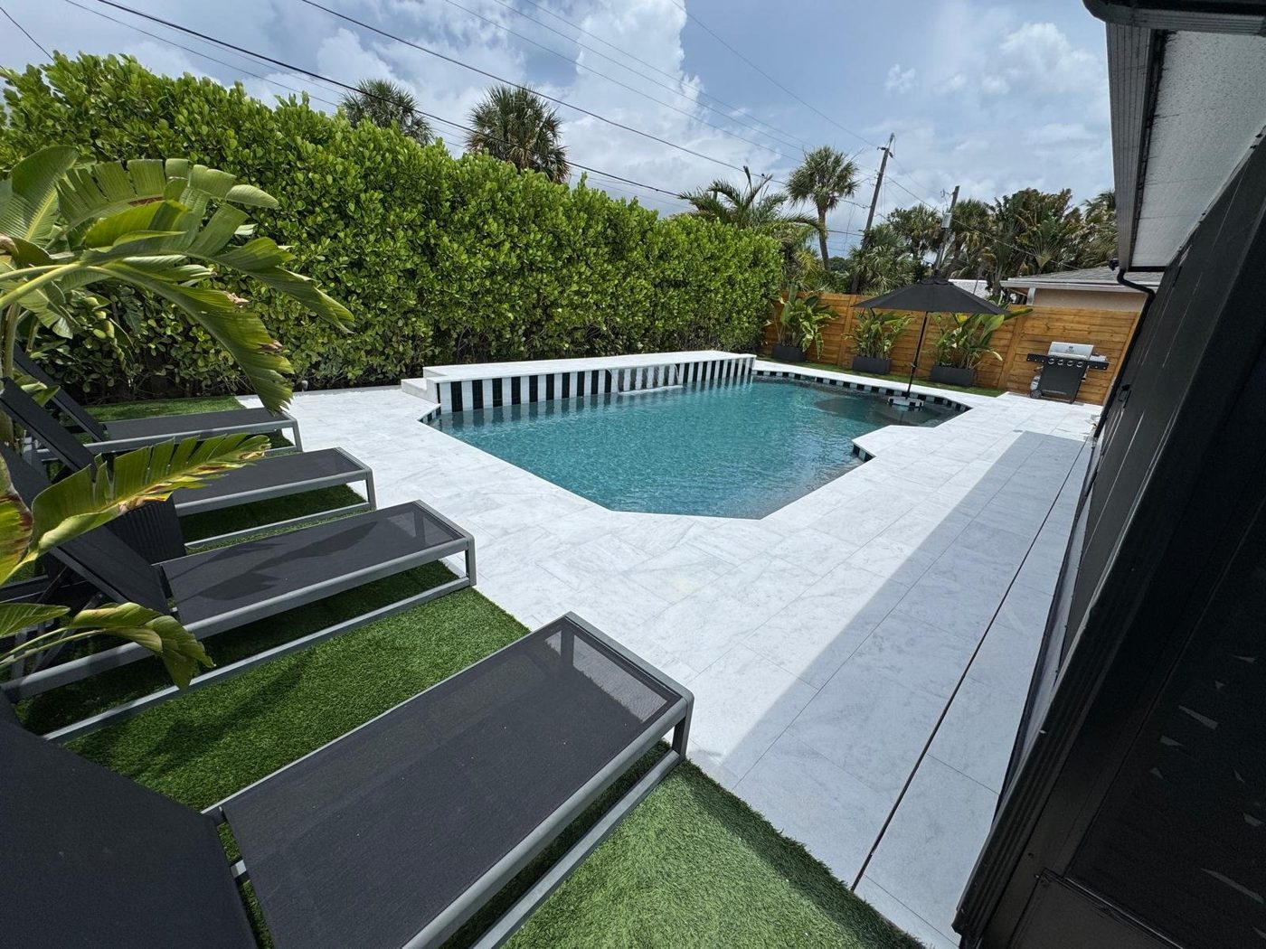PebbleSheen French Grey pool finish with a white marble deck and turf in South Florida