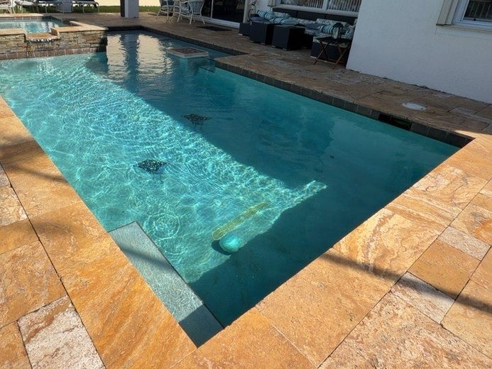 PebbleSheen Irish Mist pool finish with a gold travertine deck and turtle mosaics in Boynton Beach