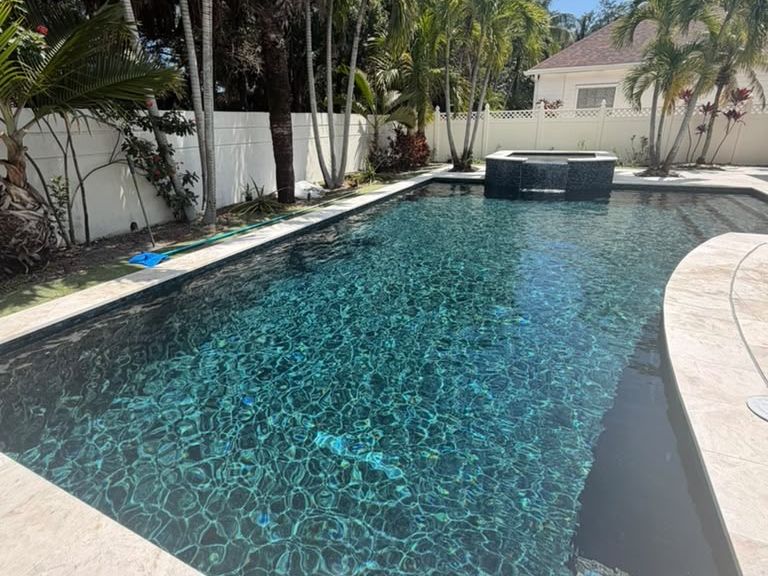 PebbleSheen Ocean Blue pool finish with a raised spa and travertine deck on a South Florida pool