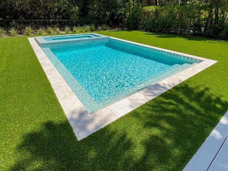 PebbleSheen White Diamonds pool finish on a rectangular pool and spa with travertine coping and turf in South Florida