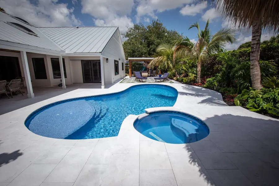 Freeform custom gunite pool with round spa and travertine deck in Jupiter