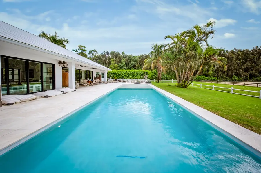 Custom gunite lap pool in Wellington with travertine deck and paddock fencing